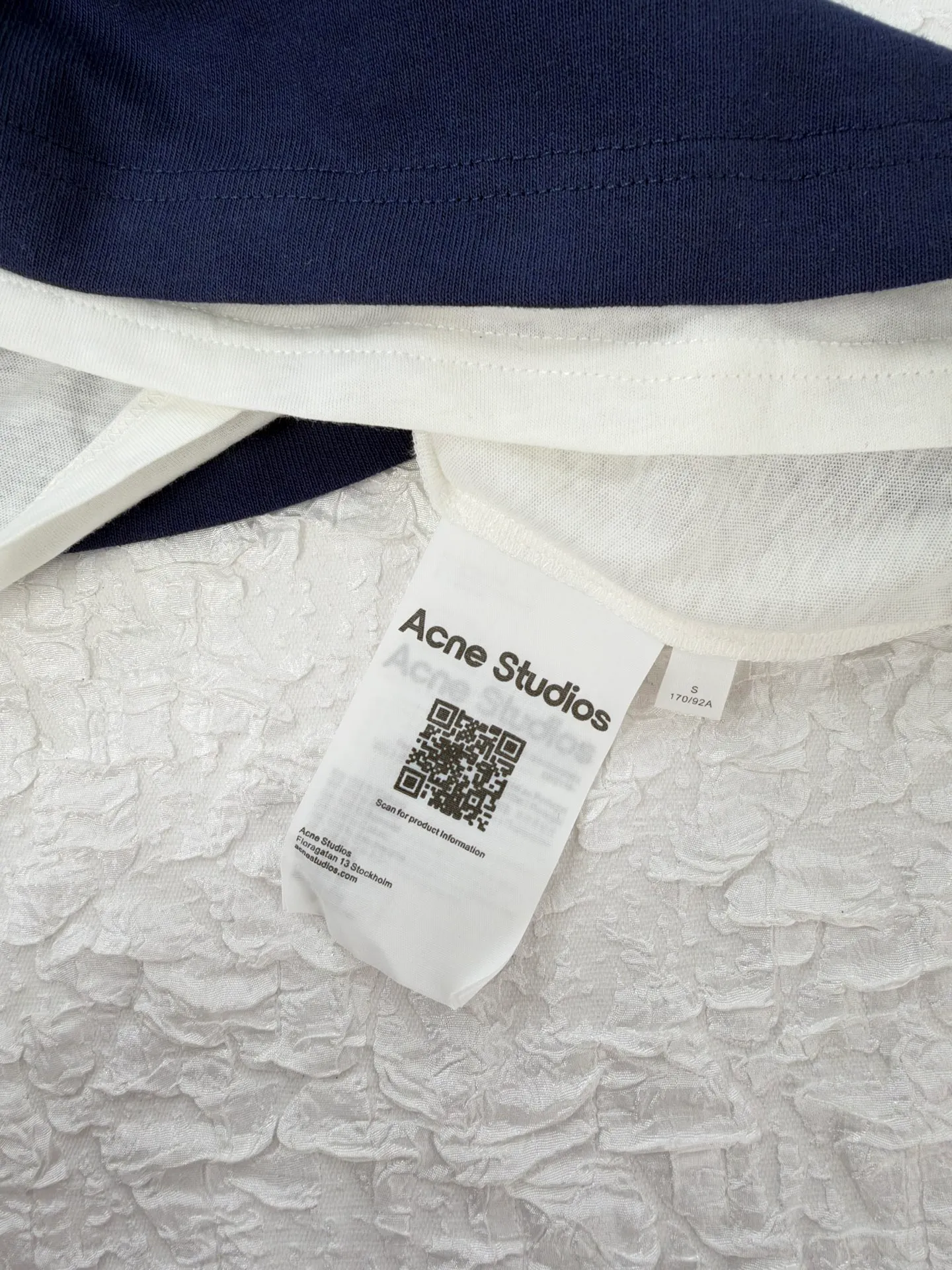 Acne Studio letter logo embroidered fake two-piece deconstructed long-sleeved T-shirt. Made of 100% cotton knitted plain fabric. The garment is pre-shrunk and washed to effectively reduce washing shrinkage. The version adopts dropped shoulder sleeves + loose box cut, the round neck is equipped with a rib collar, and the binding strip is used under the collar for reinforcement. The front chest uses high-density computer embroidery technology to present the brand logo. Visually, the inner and outer layers are designed with contrasting color splicing. The hem and cuffs are double-layered fake two-piece stacking. The sewing adopts flat seam + overlock technology. The lines are even and dense, and the overall relaxed silhouette takes into account practical wearability and layering effect. It can be worn alone or layered. Size：S/M/L/XL